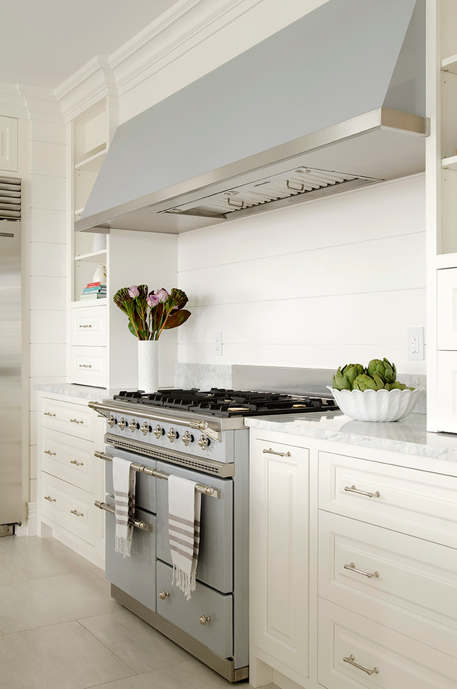 Ejemplo de cocina comedor clásica grande con armarios con paneles con relieve, puertas de armario blancas, electrodomésticos de colores y una isla