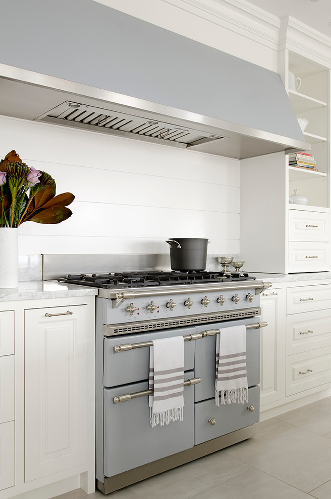Modelo de cocina comedor clásica grande con armarios con paneles con relieve, puertas de armario blancas, electrodomésticos de colores y una isla