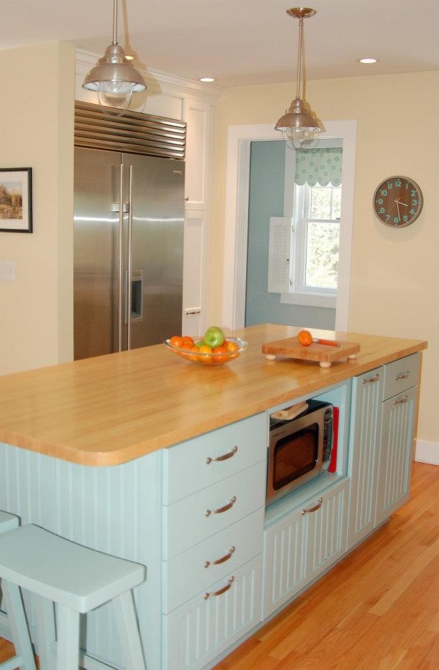 Maritim inredning av ett litet kök, med en undermonterad diskho, luckor med infälld panel, turkosa skåp, träbänkskiva, rostfria vitvaror, ljust trägolv och en köksö