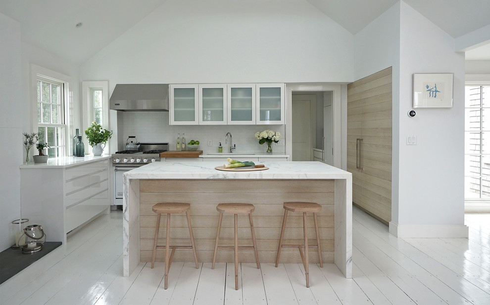 Kitchen - modern painted wood floor and white floor kitchen idea in Boston with an undermount sink, flat-panel cabinets, white cabinets, glass countertops, white backsplash, marble backsplash, stainless steel appliances, an island and white countertops