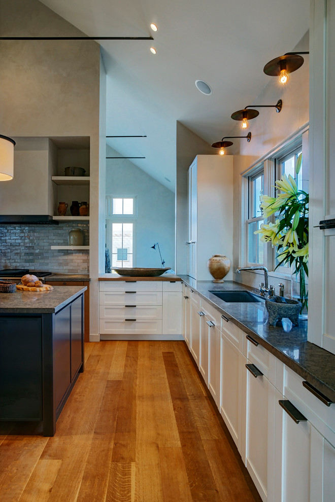 Inspiration for a mid-sized transitional u-shaped light wood floor eat-in kitchen remodel in Boston with an undermount sink, white cabinets, beaded inset cabinets, multicolored backsplash, glass tile backsplash, stainless steel appliances, an island and granite countertops