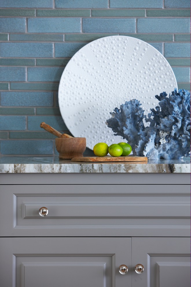 Ejemplo de cocina costera con armarios con paneles con relieve, puertas de armario grises, encimera de mármol, salpicadero azul y electrodomésticos de acero inoxidable