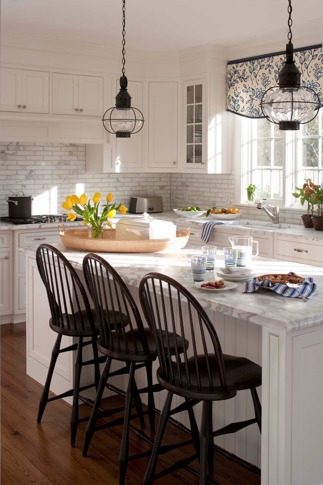 Eat-in kitchen - mid-sized traditional l-shaped dark wood floor eat-in kitchen idea in Boston with marble countertops, an undermount sink, shaker cabinets, white cabinets, white backsplash, stainless steel appliances and an island