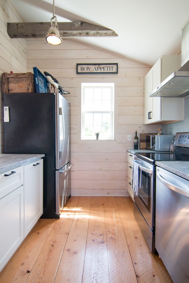 Esempio di una piccola cucina lineare country chiusa con ante bianche, elettrodomestici in acciaio inossidabile, parquet chiaro e pavimento giallo