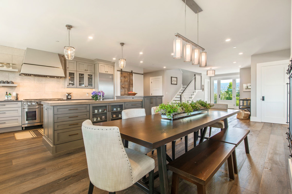 Example of a mid-sized farmhouse l-shaped dark wood floor eat-in kitchen design in San Francisco with an undermount sink, recessed-panel cabinets, green cabinets, concrete countertops, beige backsplash, stone tile backsplash, stainless steel appliances and an island