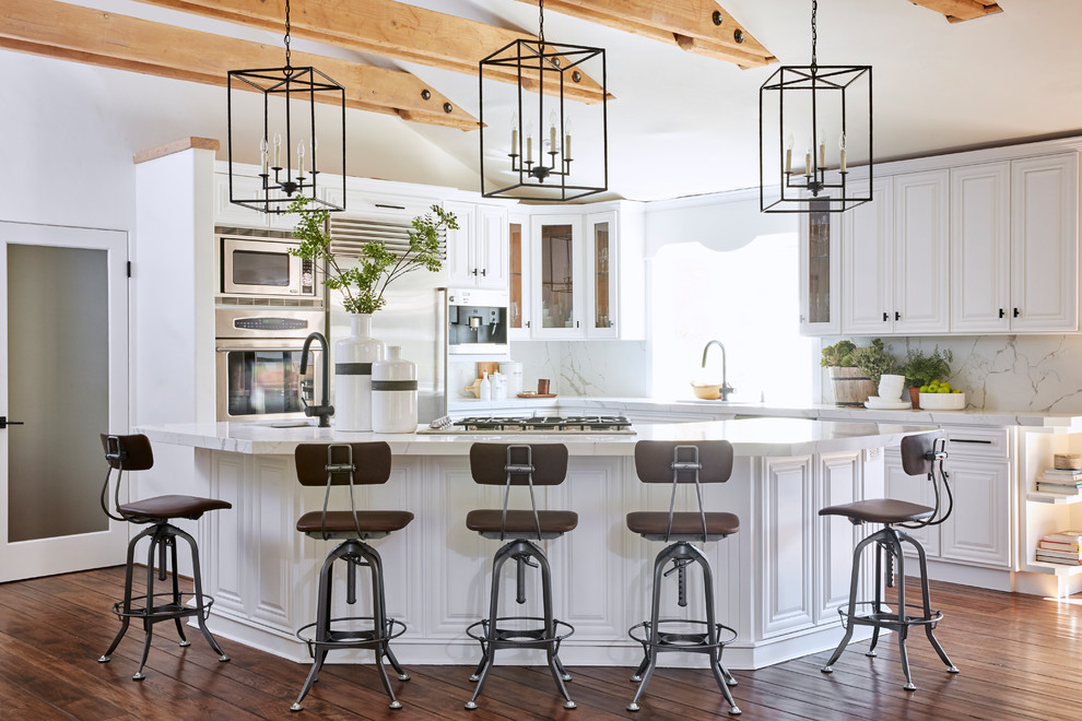 Kitchen - large mediterranean l-shaped dark wood floor and brown floor kitchen idea in Phoenix with a single-bowl sink, raised-panel cabinets, white cabinets, quartz countertops, white backsplash, stone slab backsplash, stainless steel appliances, an island and white countertops