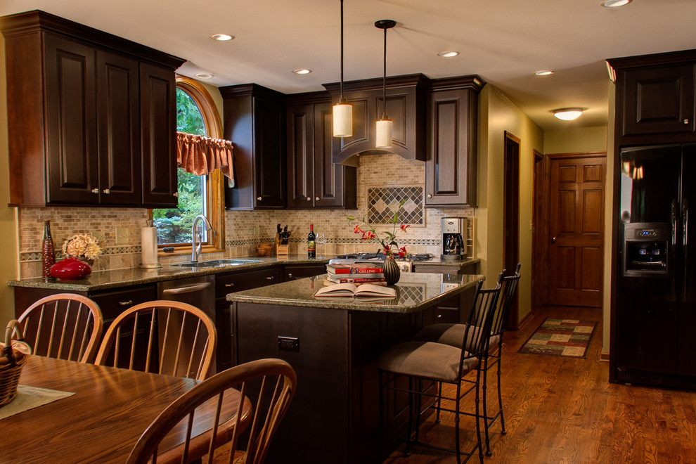 Eat-in kitchen - large traditional l-shaped dark wood floor eat-in kitchen idea in Chicago with an undermount sink, recessed-panel cabinets, dark wood cabinets, granite countertops, brown backsplash, matchstick tile backsplash, black appliances and an island