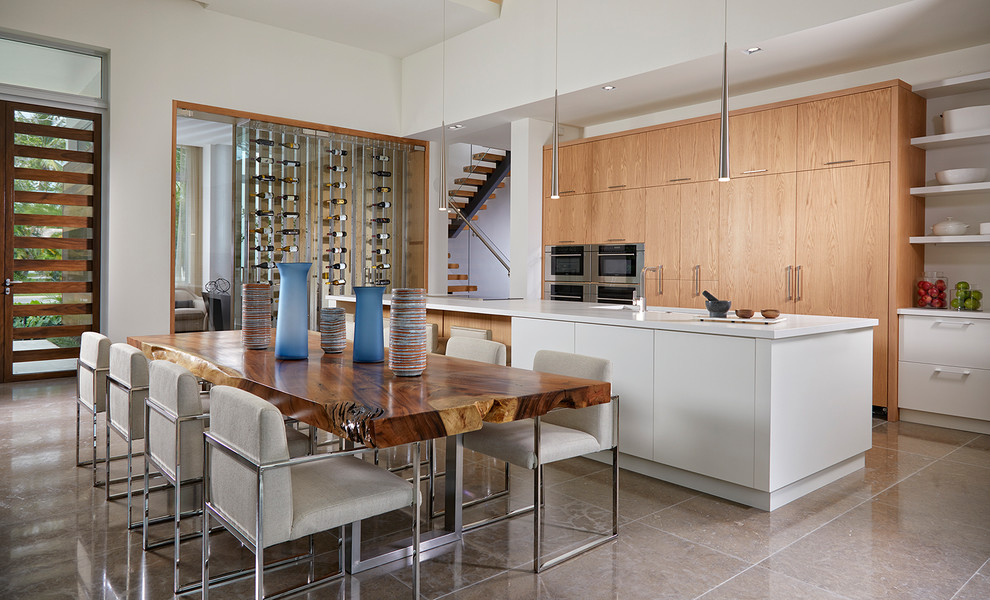 Zweizeilige Moderne Wohnküche mit flächenbündigen Schrankfronten, hellbraunen Holzschränken, Kalkstein-Arbeitsplatte, Küchengeräten aus Edelstahl, Marmorboden, Kücheninsel und grauem Boden in Miami