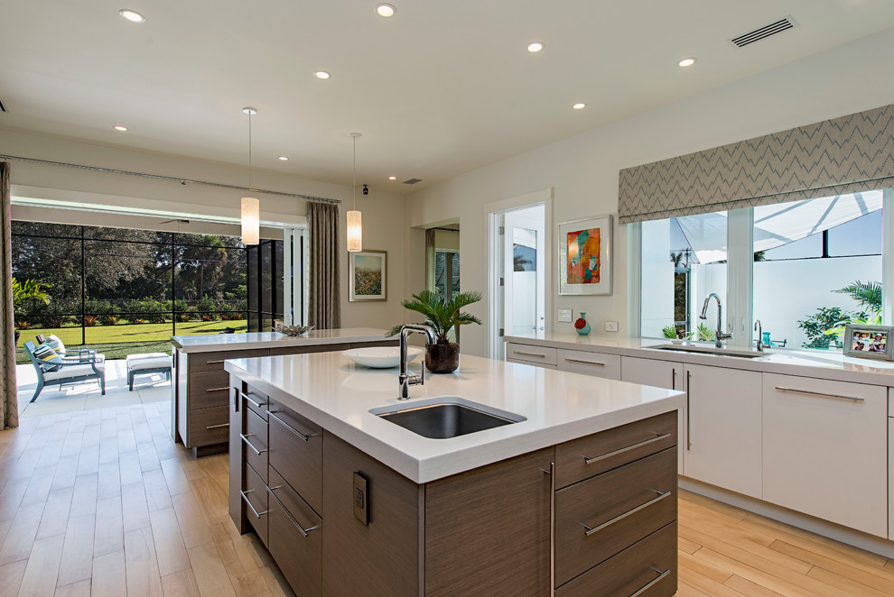 Photo of a contemporary kitchen in Miami with a submerged sink, flat-panel cabinets, white cabinets, light hardwood flooring and multiple islands.
