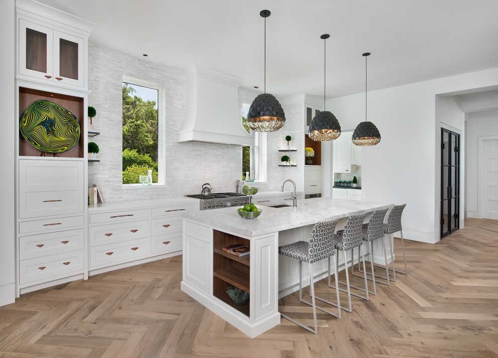 Inspiration for a medium sized traditional galley kitchen/diner in Miami with a belfast sink, white cabinets, marble worktops, grey splashback, stone slab splashback, stainless steel appliances, light hardwood flooring, an island, beige floors, grey worktops and shaker cabinets.
