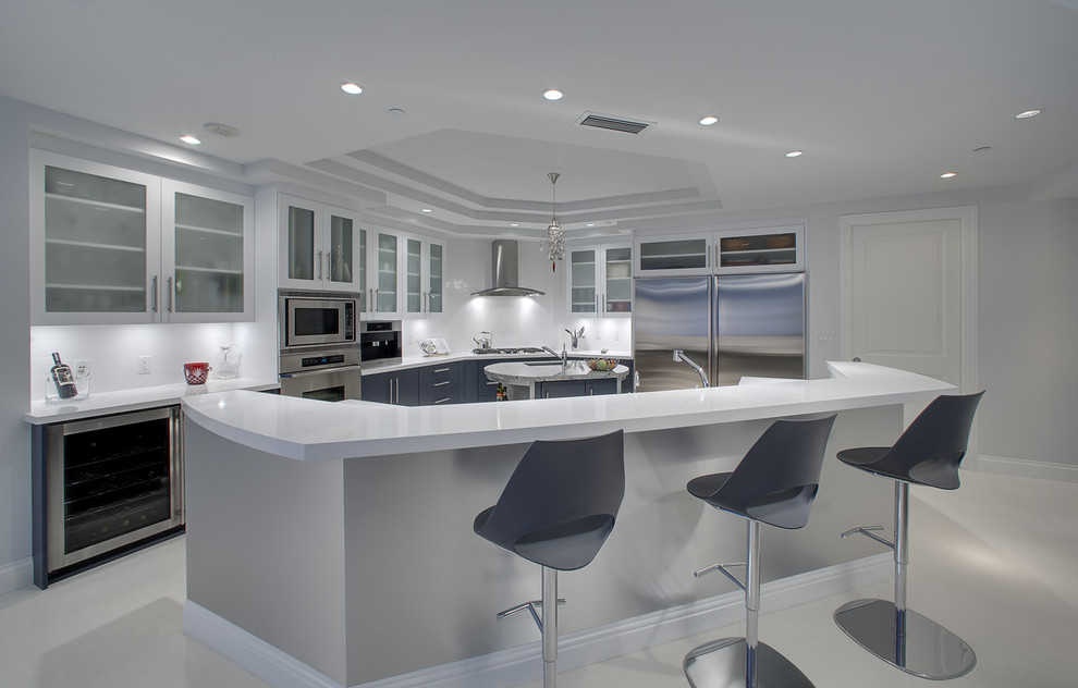 Modelo de cocina contemporánea con armarios tipo vitrina, puertas de armario blancas y electrodomésticos de acero inoxidable