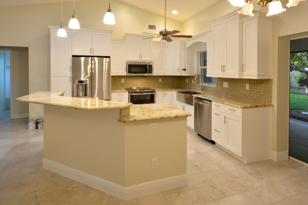 Photo of a medium sized traditional l-shaped kitchen/diner in Tampa with a belfast sink, flat-panel cabinets, white cabinets, granite worktops, beige splashback, ceramic splashback, stainless steel appliances, porcelain flooring and an island.