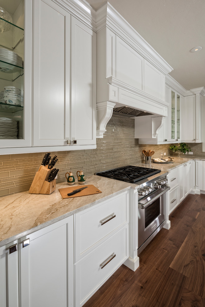 Foto de cocina tropical con puertas de armario blancas, electrodomésticos de acero inoxidable y suelo de madera oscura