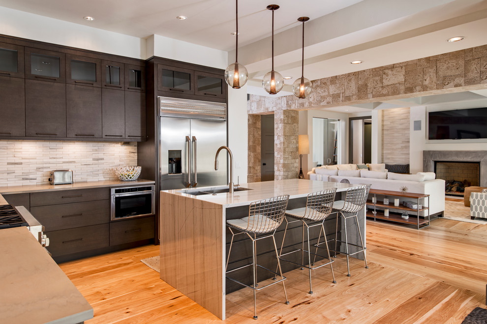 Example of a mid-sized minimalist l-shaped light wood floor open concept kitchen design in Miami with an undermount sink, glass-front cabinets, dark wood cabinets, granite countertops, stainless steel appliances and an island