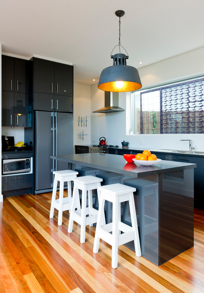 Immagine di una cucina minimalista di medie dimensioni con paraspruzzi bianco, elettrodomestici in acciaio inossidabile e pavimento in legno massello medio