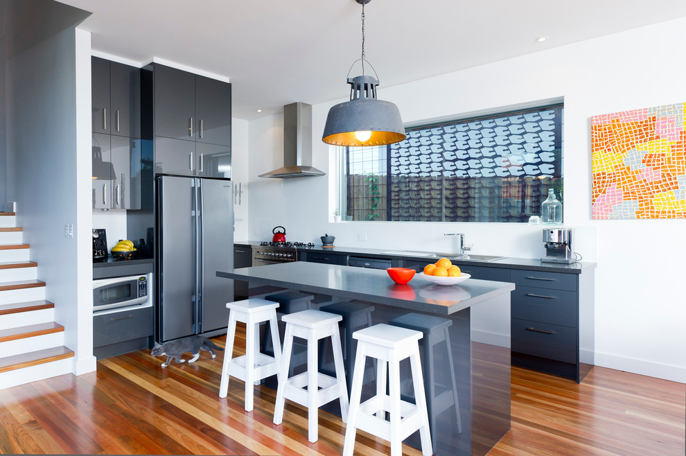 Esempio di una cucina moderna di medie dimensioni con paraspruzzi bianco, elettrodomestici in acciaio inossidabile e pavimento in legno massello medio