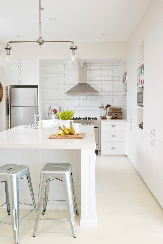 Imagen de cocina de estilo de casa de campo con puertas de armario blancas, salpicadero blanco, salpicadero de azulejos tipo metro, electrodomésticos de acero inoxidable y una isla