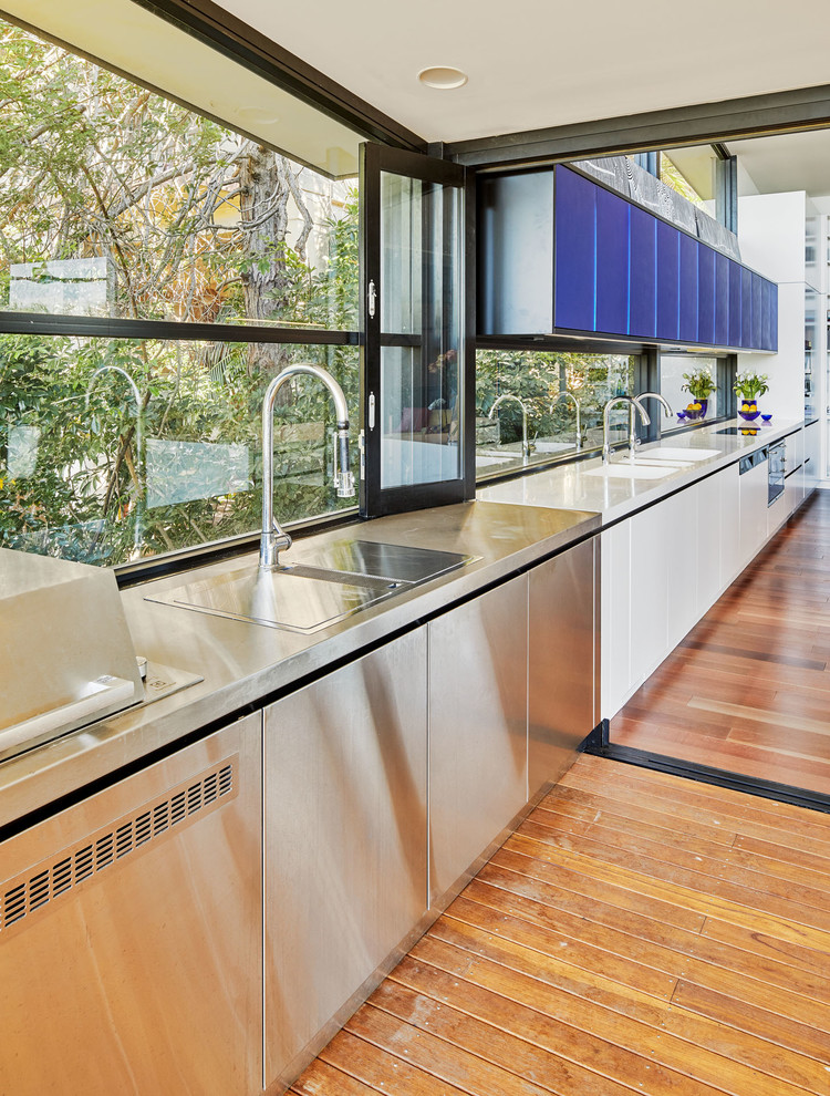 Foto di una grande cucina moderna con lavello a doppia vasca, ante lisce, ante blu, top in superficie solida, elettrodomestici da incasso, pavimento in legno massello medio e pavimento marrone