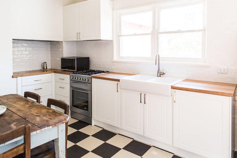 This is an example of a small rustic single-wall kitchen/diner in Canberra - Queanbeyan with a belfast sink, white cabinets, wood worktops, white splashback and metro tiled splashback.