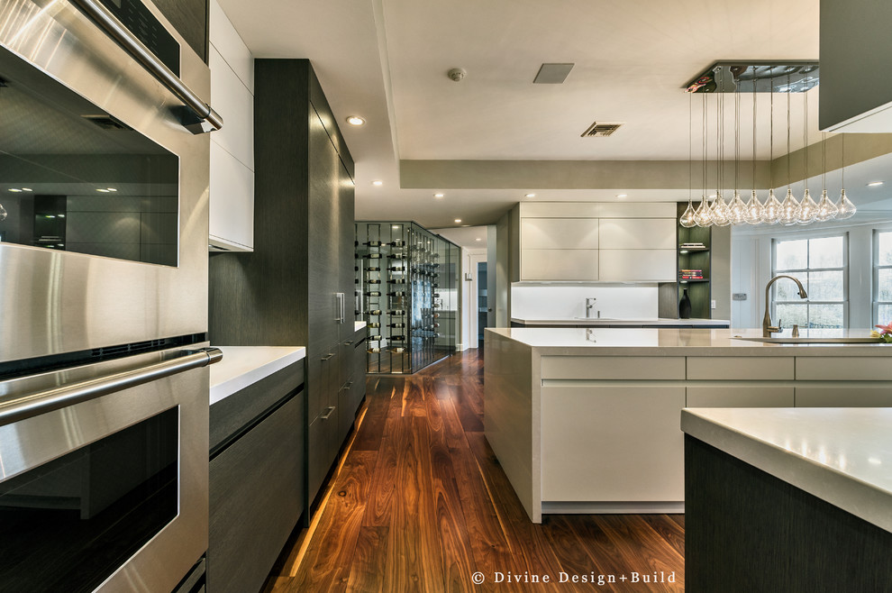 Photo of a contemporary kitchen in Boston with an island, a submerged sink, flat-panel cabinets, grey cabinets, white splashback, glass sheet splashback, stainless steel appliances and medium hardwood flooring.