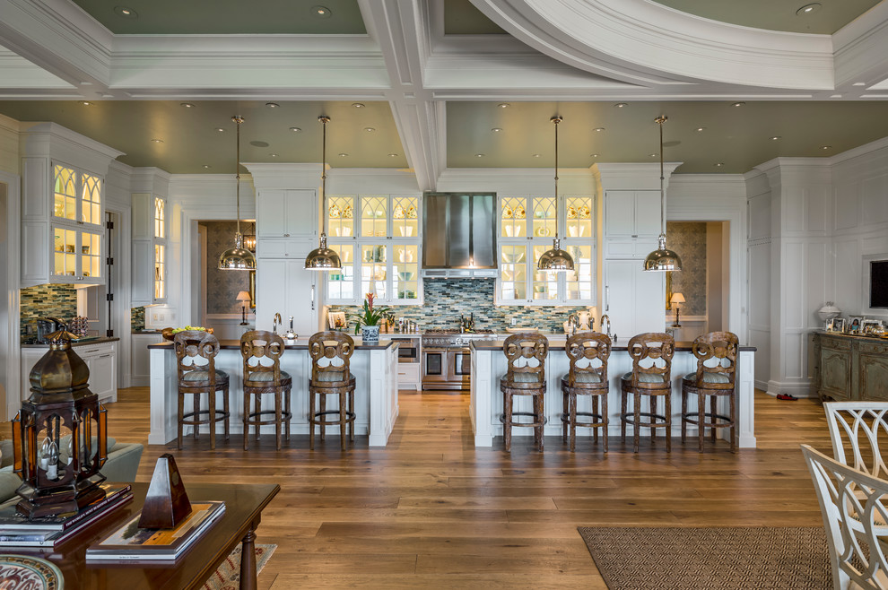 На фото: огромная п-образная кухня в классическом стиле с обеденным столом, фасадами с утопленной филенкой, желтыми фасадами, мраморной столешницей и двумя и более островами с