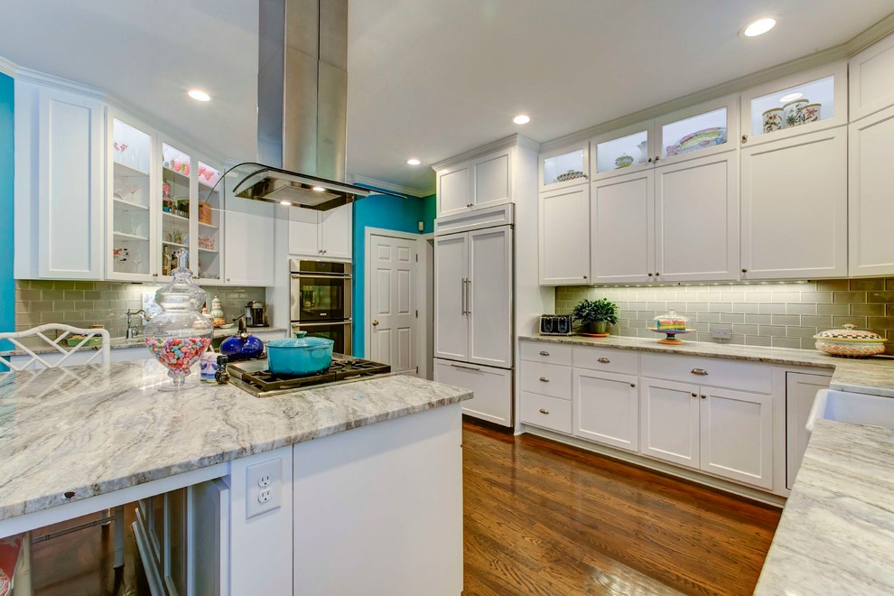Enclosed kitchen - large transitional l-shaped medium tone wood floor enclosed kitchen idea in Raleigh with a farmhouse sink, shaker cabinets, white cabinets, granite countertops, gray backsplash, subway tile backsplash, white appliances and an island