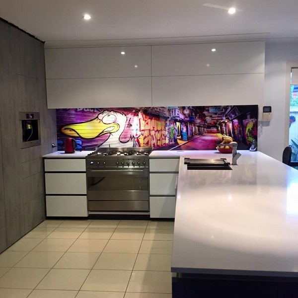 Photo of a large contemporary l-shaped open plan kitchen in Melbourne with an island, a double-bowl sink, flat-panel cabinets, white cabinets, engineered stone countertops, glass sheet splashback, stainless steel appliances, porcelain flooring, beige floors and multi-coloured splashback.