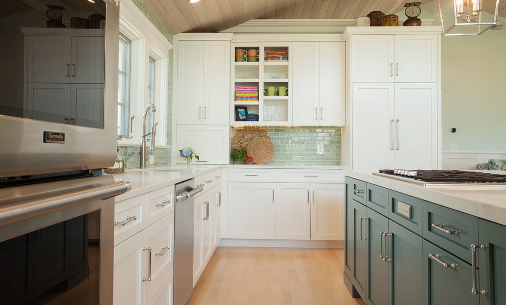 Bild på ett mellanstort maritimt vit vitt kök, med en undermonterad diskho, skåp i shakerstil, gula skåp, bänkskiva i kvarts, grönt stänkskydd, stänkskydd i tunnelbanekakel, vita vitvaror, ljust trägolv och en köksö