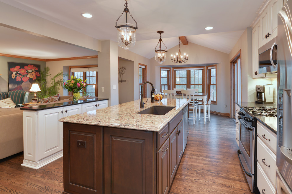 Eat-in kitchen - large traditional single-wall medium tone wood floor and brown floor eat-in kitchen idea in Milwaukee with an undermount sink, raised-panel cabinets, white cabinets, quartzite countertops, beige backsplash, stone tile backsplash, stainless steel appliances, an island and beige countertops