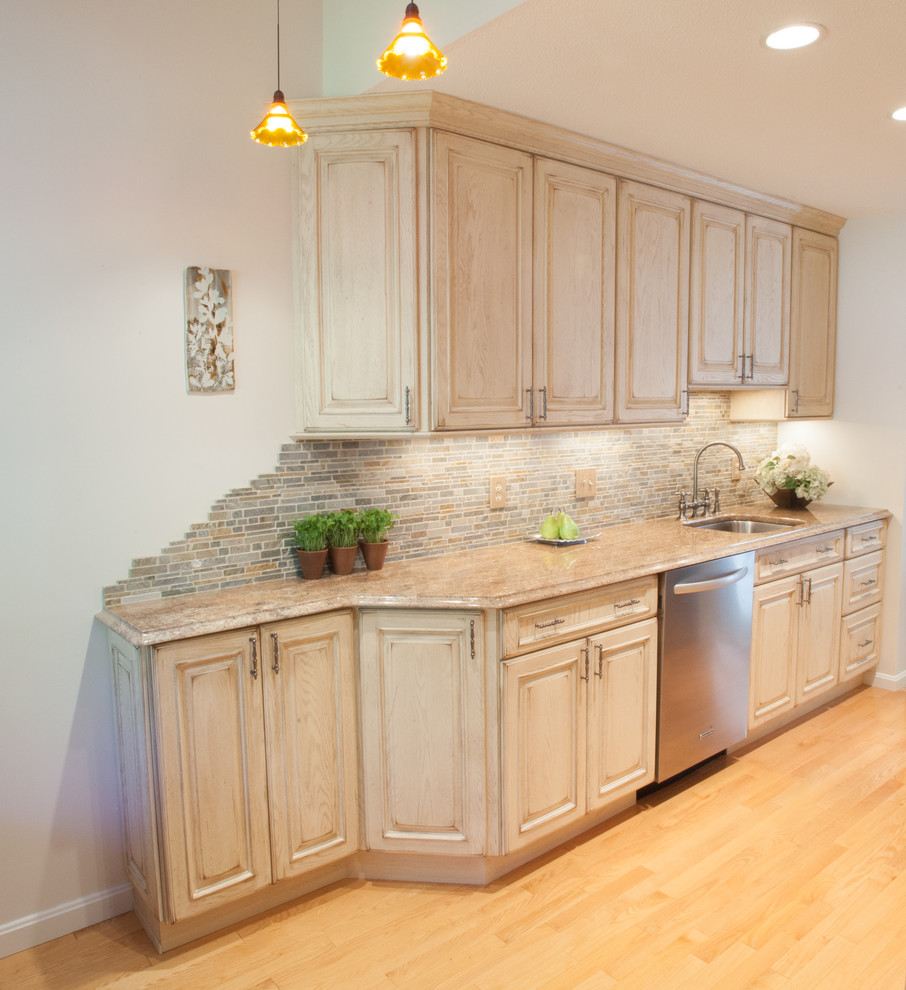 Bild på ett litet rustikt kök, med en enkel diskho, skåp i slitet trä, granitbänkskiva, flerfärgad stänkskydd, rostfria vitvaror, ljust trägolv, luckor med upphöjd panel, stänkskydd i stenkakel och beiget golv