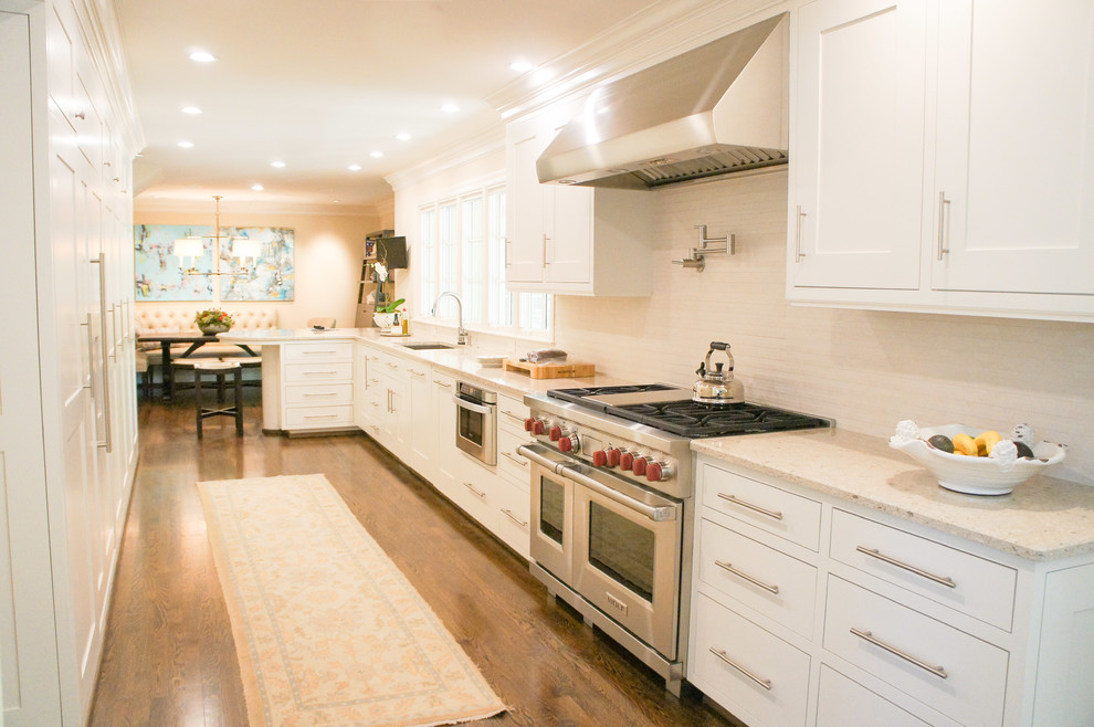 Bild på ett stort vintage kök, med en undermonterad diskho, skåp i shakerstil, vita skåp, granitbänkskiva, vitt stänkskydd, stänkskydd i keramik, rostfria vitvaror och mellanmörkt trägolv
