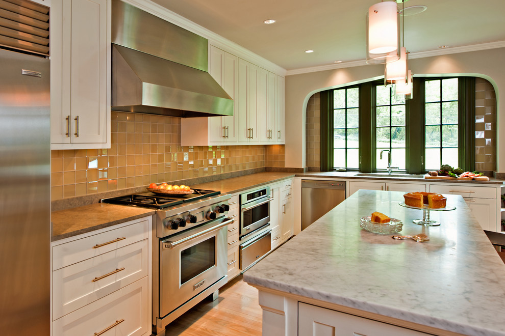 Inspiration for a timeless l-shaped eat-in kitchen remodel in Nashville with an undermount sink, flat-panel cabinets, white cabinets, limestone countertops, gray backsplash, glass sheet backsplash and stainless steel appliances