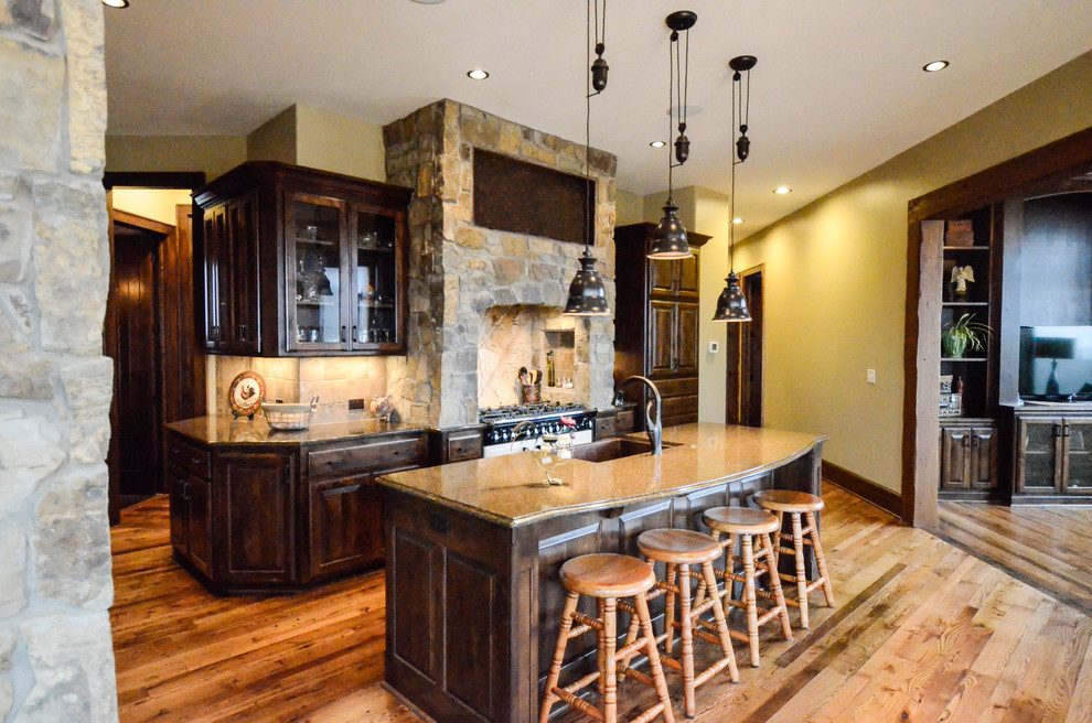 Inspiration for a large rustic single-wall medium tone wood floor eat-in kitchen remodel in Kansas City with a farmhouse sink, shaker cabinets, dark wood cabinets, quartz countertops, brown backsplash, ceramic backsplash, paneled appliances and an island