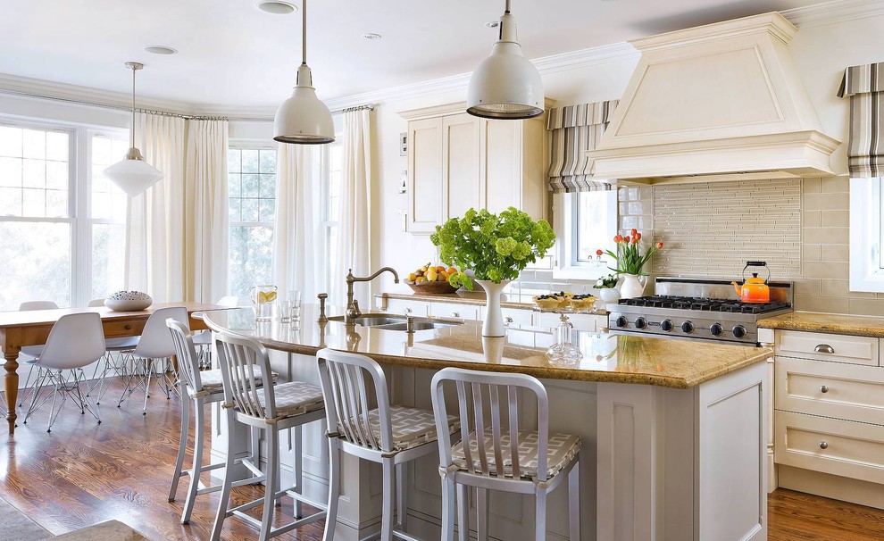 На фото: кухня в классическом стиле с обеденным столом, двойной мойкой, фасадами с утопленной филенкой, белыми фасадами, бежевым фартуком и фартуком из удлиненной плитки