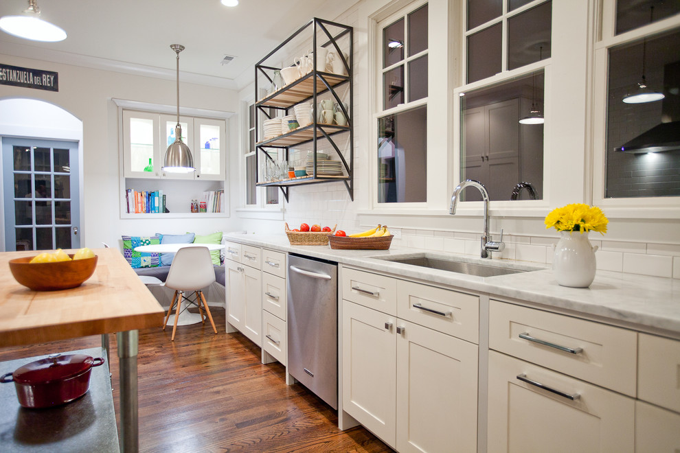 Large trendy galley medium tone wood floor kitchen photo in New York with an undermount sink, shaker cabinets, white cabinets, white backsplash, stainless steel appliances, marble countertops and an island