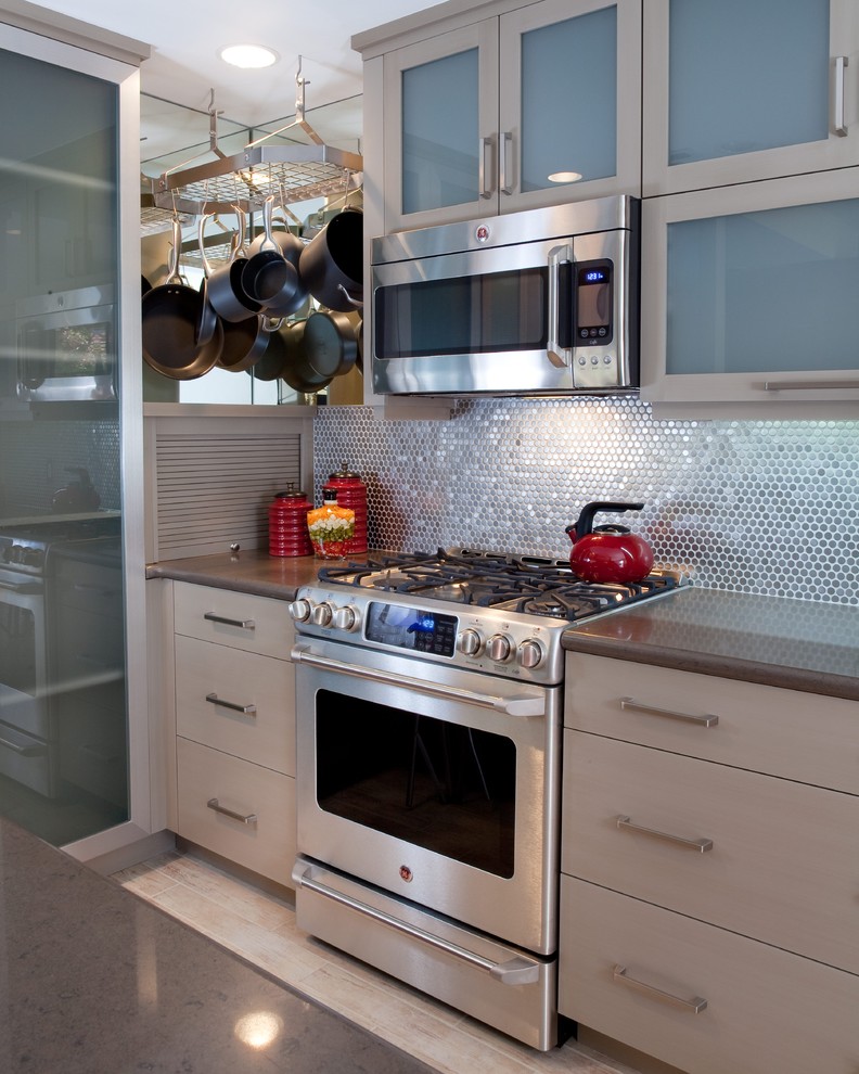 Bild på ett litet funkis u-kök, med luckor med glaspanel, grå skåp, bänkskiva i kvartsit, stänkskydd med metallisk yta, stänkskydd i metallkakel, rostfria vitvaror och vinylgolv