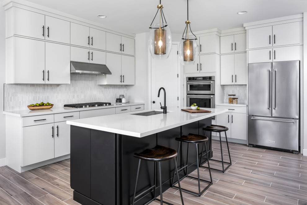 Inspiration for a contemporary l-shaped gray floor kitchen remodel in Phoenix with an undermount sink, flat-panel cabinets, white cabinets, white backsplash, stainless steel appliances, an island and white countertops
