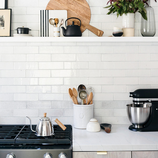 Immagine di una cucina ad U scandinava con ante lisce, ante in legno chiaro, top in quarzo composito e elettrodomestici neri