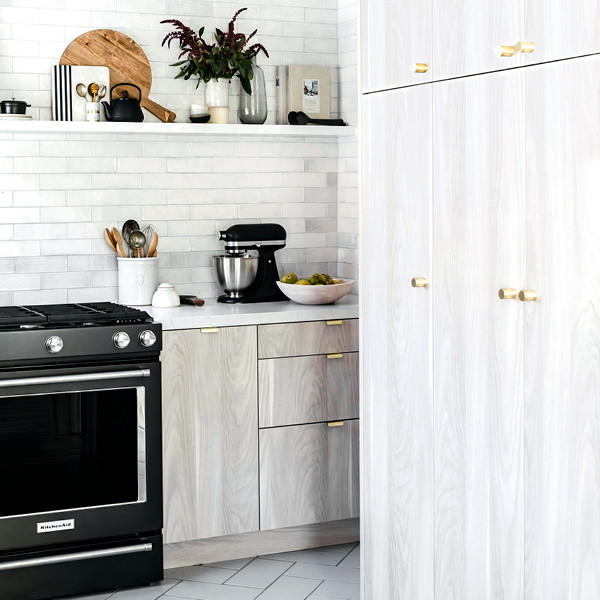 Ejemplo de cocinas en U escandinavo con armarios con paneles lisos, puertas de armario de madera clara, encimera de cuarzo compacto y electrodomésticos negros