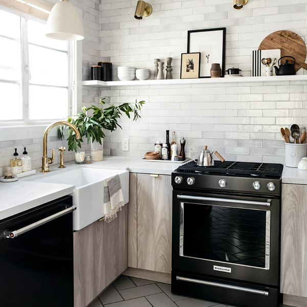 Photo of a scandinavian u-shaped kitchen in Los Angeles with flat-panel cabinets, light wood cabinets, engineered stone countertops and black appliances.
