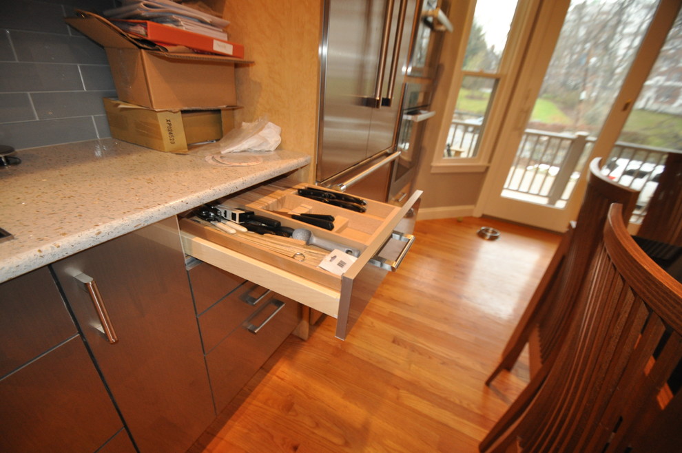 Bild på ett mellanstort funkis kök, med en nedsänkt diskho, släta luckor, skåp i ljust trä, bänkskiva i terrazo, stänkskydd i tunnelbanekakel, rostfria vitvaror, mellanmörkt trägolv, en halv köksö och grått stänkskydd