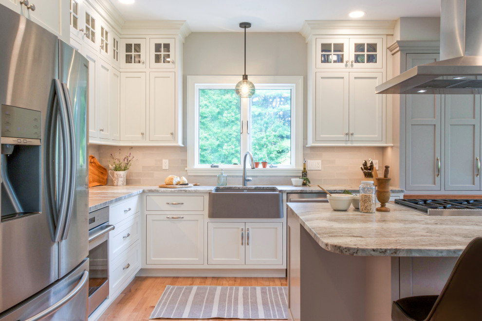 Example of a mid-sized classic l-shaped medium tone wood floor and brown floor open concept kitchen design in Boston with a farmhouse sink, gray cabinets, gray backsplash, subway tile backsplash, stainless steel appliances, an island, gray countertops and quartzite countertops