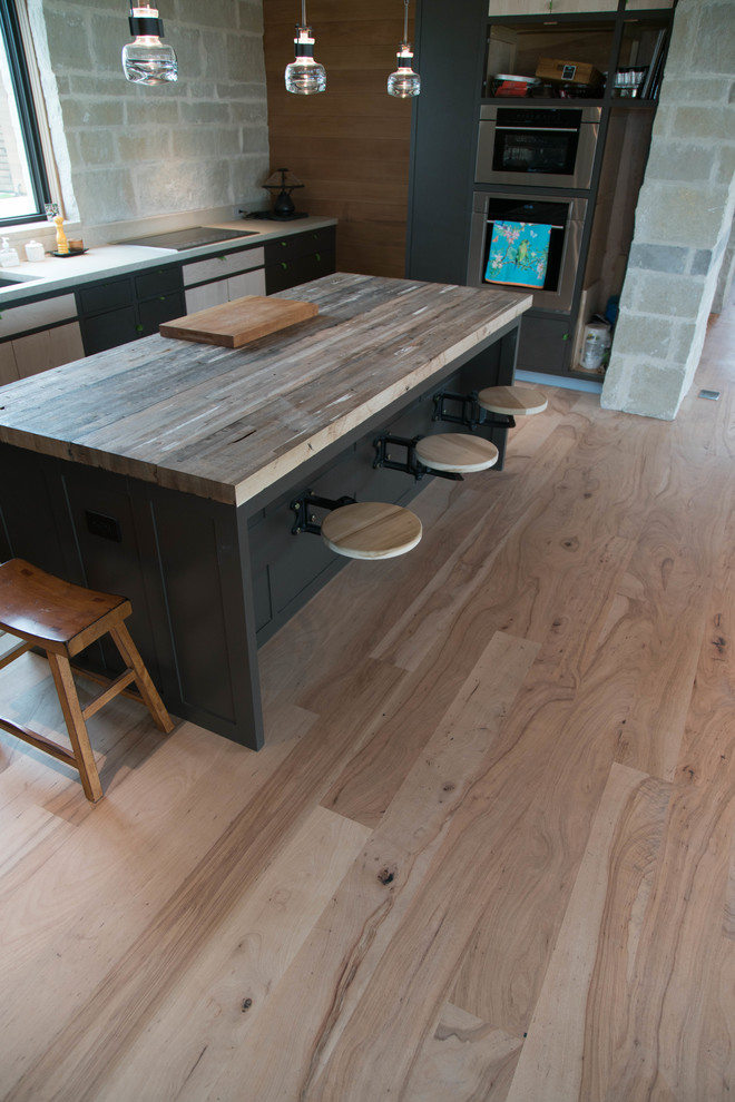 Example of an urban light wood floor kitchen design in Austin with wood countertops, stainless steel appliances and an island