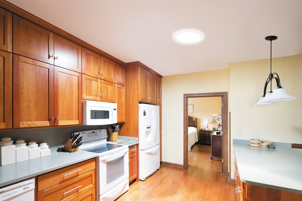 Einzeilige, Mittelgroße Moderne Wohnküche mit flächenbündigen Schrankfronten, braunen Schränken, Laminat-Arbeitsplatte, weißen Elektrogeräten, hellem Holzboden und Kücheninsel in Austin