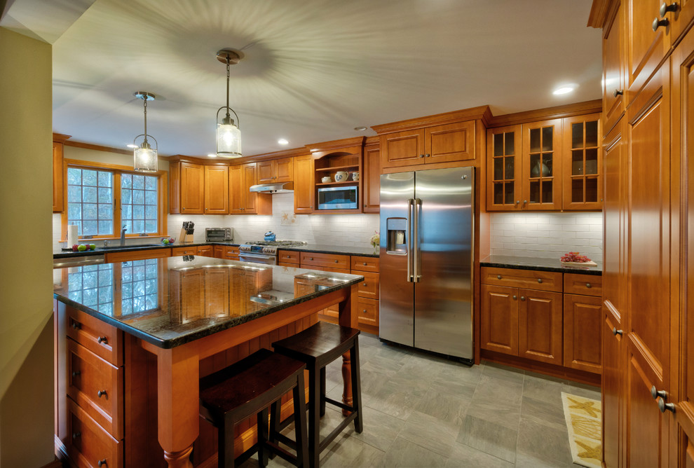 Foto på ett stort vintage kök, med en undermonterad diskho, luckor med upphöjd panel, skåp i mellenmörkt trä, granitbänkskiva, vitt stänkskydd, stänkskydd i keramik, rostfria vitvaror, klinkergolv i keramik, en köksö och grått golv