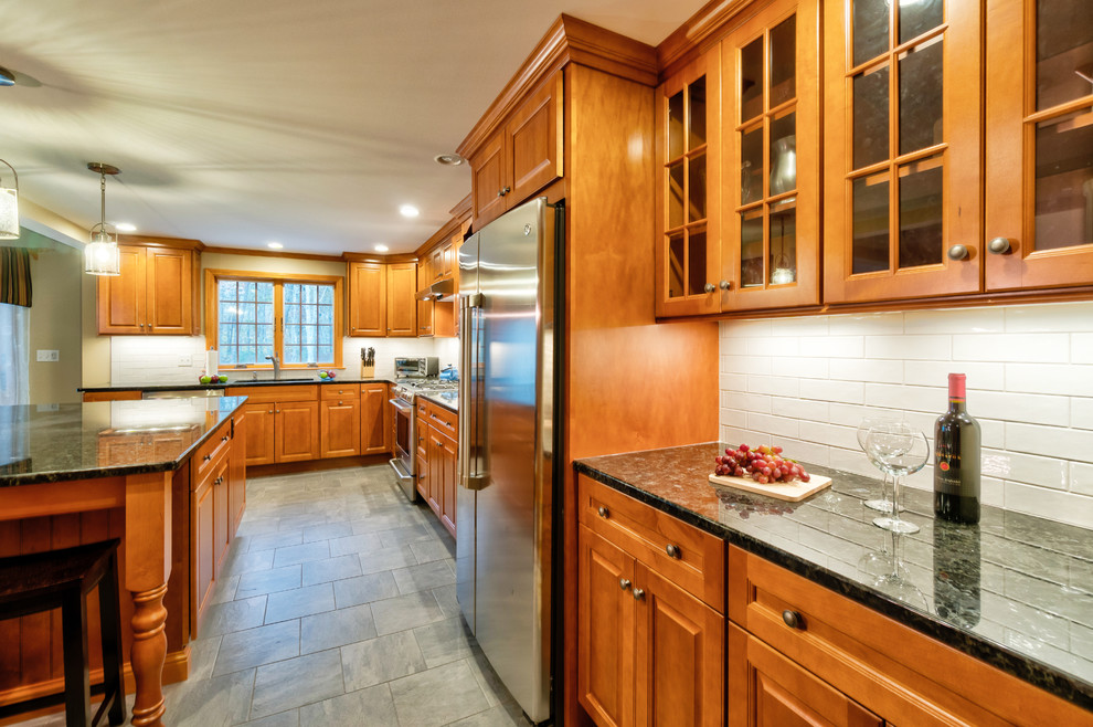 Example of a large classic u-shaped ceramic tile and gray floor open concept kitchen design in Boston with an undermount sink, raised-panel cabinets, medium tone wood cabinets, granite countertops, white backsplash, ceramic backsplash, stainless steel appliances and an island
