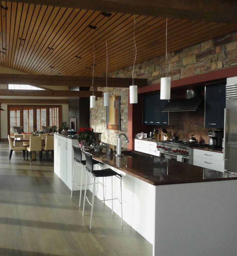 Example of a large minimalist l-shaped porcelain tile open concept kitchen design in Other with an undermount sink, flat-panel cabinets, white cabinets, granite countertops, brown backsplash, stainless steel appliances and an island