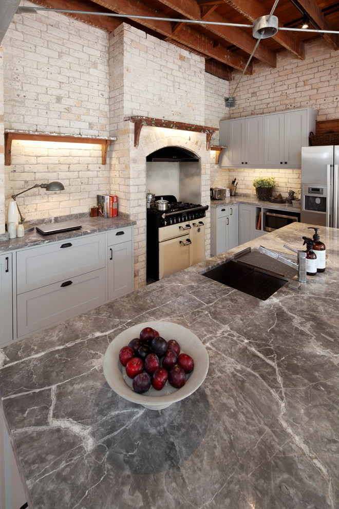 Ejemplo de cocina industrial con encimera de mármol, electrodomésticos de acero inoxidable y suelo de madera en tonos medios