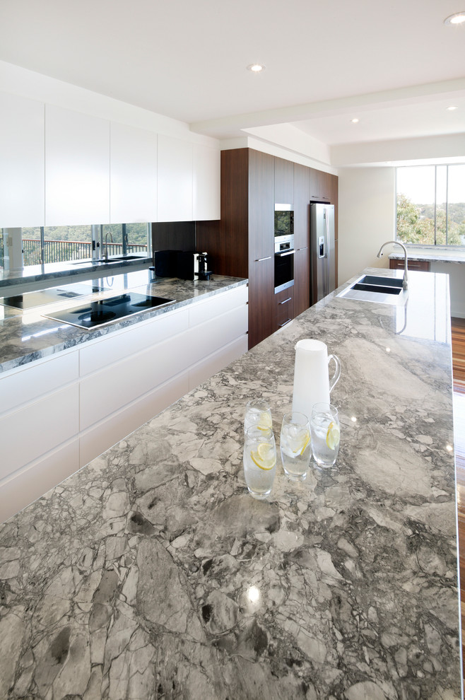 Imagen de cocina comedor contemporánea con encimera de mármol, salpicadero metalizado, salpicadero con efecto espejo, suelo de madera en tonos medios y una isla