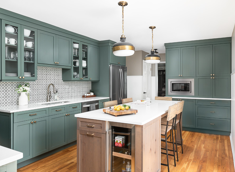 Inspiration for a mid-sized transitional l-shaped light wood floor enclosed kitchen remodel in Chicago with an undermount sink, shaker cabinets, green cabinets, quartz countertops, white backsplash, cement tile backsplash, stainless steel appliances, an island and white countertops
